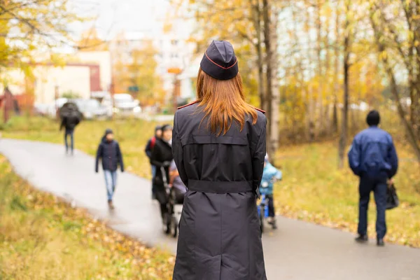 Mujer policía de pie con la espalda en uniforme negro Imágenes De Stock Sin Royalties Gratis