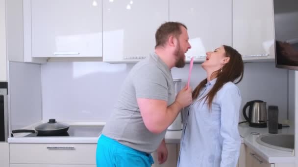 Uomini e donne paffuti che ballano e cantano in cucina mentre cucinano a casa, il concetto di una famiglia felice e divertente — Video Stock