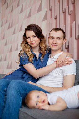 Üç kişilik mutlu bir aile odadaki kanepede dinleniyor.