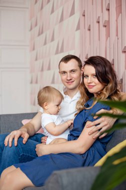 Üç kişilik mutlu bir aile odadaki kanepede dinleniyor.