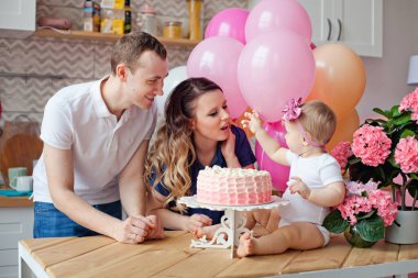 Aile masada, doğum günü pastası ve balonlarla.