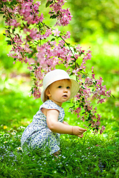 Крупный план портрета 1-2-летней девочки на свежем воздухе в саду с розовыми цветами на деревьях
.