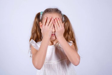 Stüdyonun arka planında duran, elleriyle gözlerini kapatan genç bir kızın portresi. Karışık kız elleriyle gözlerini kapatıyor, bir şeyi görmezden geliyor..
