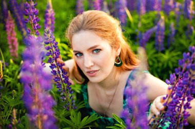 Sarı elbiseli genç bir kız çiçek açan bir tarlada büyük bir demet mor lupin tutuyor. Çiçek açan Lupin çiçekleri. Çevre dostu. Doğa kavramı. Yumuşak odak.