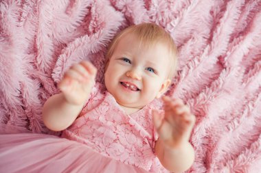 Minik tatlı bir kızın portresi pembe tüylü bir battaniyeye uzanıyor, yukarıdan görünüyor, bebek fotoğrafçılığı konsepti