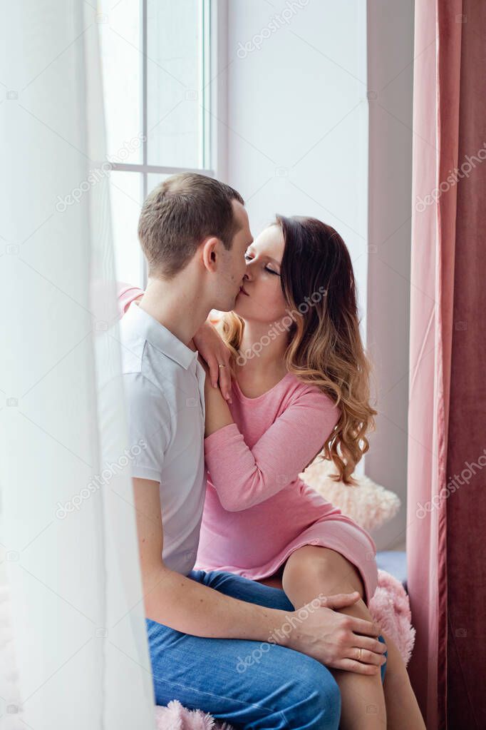 Loving couple kissing on the windowsill. Love story. Side view