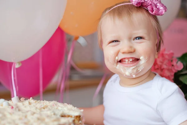 little girl on the table with a birthday cake and balloons