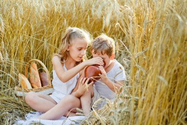 Buğday tarlasında çocuklar. Erkek ve kız kardeşler ekmek yer, rulo yapar, simit yer ve bir sütten süt içerler. Bir erkek ve bir kız hasat zamanı dışarıda oynuyorlar..