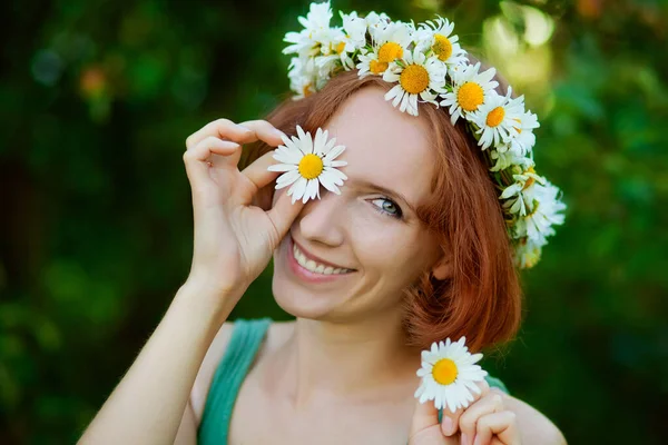 a red-haired girl with a bouquet of daisies and a wreath on her head.