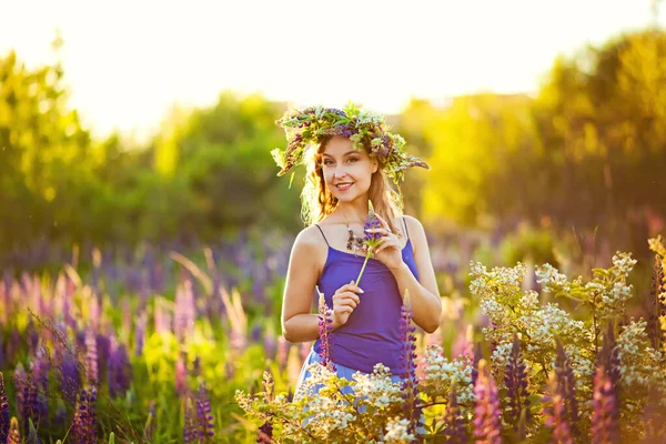 若い美少女が春の夕日に花冠を頭につけたチューリップの春の牧草地に立っています — ストック写真