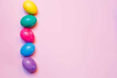 Renkli Paskalya yumurtaları ve pembe arkaplandaki yazı için alan ile süslenmiş.