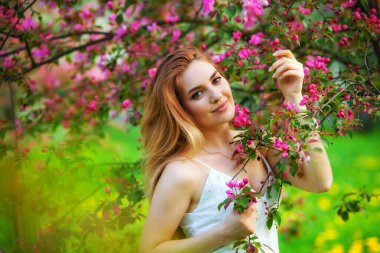 Güzel kızıl saçlı genç kız çiçek açan ağaçlara karşı bahar bahçesinde hayatın tadını çıkarıyor. Gün batımında genç, hayalperest, düşünceli bayan. Kırsal alanda bahar mevsimi