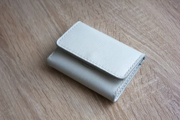 White leather wallet on a wooden tableWhite handmade leather wallet on a light wooden table