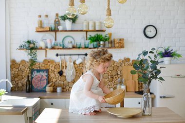 Parlak İskandinav tarzı bir mutfakta küçük bir kız masada oturuyor. Bulaşıklarla, mısır gevrekleriyle, fasulyelerle oynuyorlar. Çocuk gelişimi kavramı Montessori.