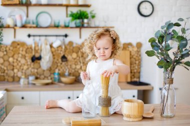 Evde çevre dostu tahta oyuncaklarla oynayan sevimli küçük bir kız bebek. Bebek rol yapma ve yemek pişirme oyunlarıyla eğleniyor..