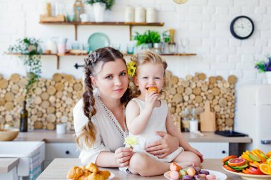 Kahvaltı sırasında mutfakta poz veren mutlu bir anne ve kızın aile portresi. Lezzetli kurabiyeler, kurabiyeler..