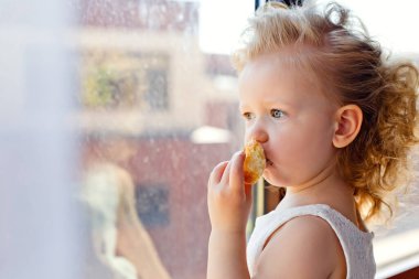Küçük bir kız kahvaltı sırasında mutfakta poz veriyor, lezzetli kurabiyeler, kurabiyeler yiyor..