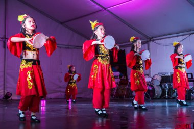 Auckland, Yeni Zelanda 'daki ay festivali kutlamaları sırasında sahnede sahne alan parlak kırmızı geleneksel Çin halk dansları kostümlü genç Asyalı kızlar. 14 Eylül 2019 