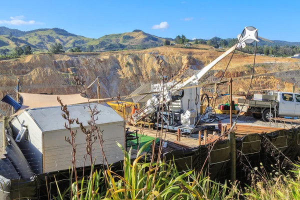 Mineral exploration. A portable drilling rig taking samples on the rim of the open-cast Martha gold mine in Waihi, New Zealand