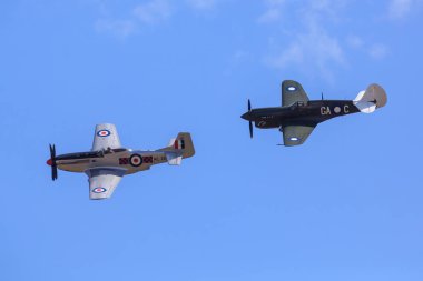 Tarihsel WW2 savaş uçakları, bir P-51 Mustang ve bir Curtiss P-40 Kittyhawk, bir hava gösterisinde havada süzülürler. Maunganui Dağı, Yeni Zelanda, 18 Ocak 2020
