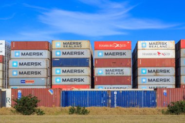Shipping containers, from Maersk, Triton, P&O and other companies, stacked up in an outdoor lot. Mount Maunganui, New Zealand, January 20 2020