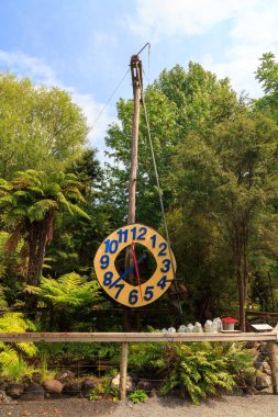 A giant rustic outdoor clock, powered by a jet of water spraying a pendulum. Photographed at 