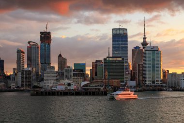Auckland, Yeni Zelanda 'nın silueti, gün batımında Waitemata Limanı' ndan görüldü. Gökyüzü Kulesi sağda ve Fuller feribotu suyun üzerinde. 14 Mart 2020