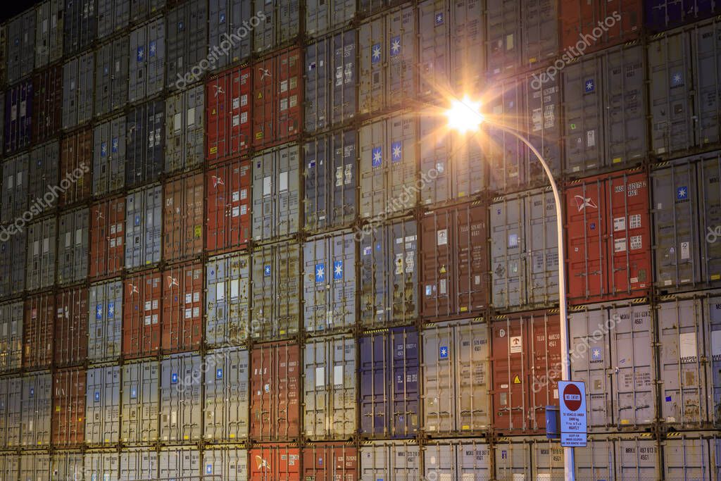 A towering wall of neatly stacked shipping containers, lit up by a streetlight. Mount Maunagnui, New Zealand, May 10 2020