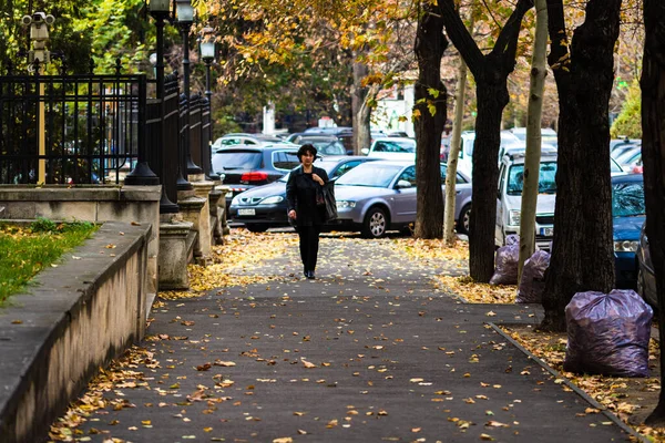 Γυναίκα περπατώντας το πρωί του φθινοπώρου στο πεζοδρόμιο με το φθινόπωρο — Φωτογραφία Αρχείου
