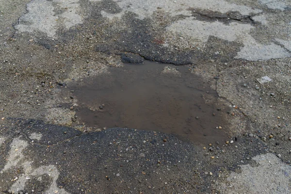 Damaged asphalt pavement road with pothole. Pothole with rainwat — Stock Photo, Image