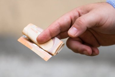 Adam eli rüşvet ya da bahşiş gibi para veriyor. Avro banknotunu elinde tutmak