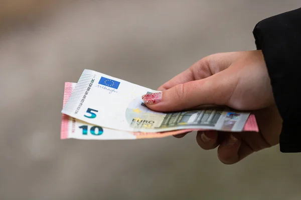 Girl hands giving money. Holding EURO banknotes on a blurred bac