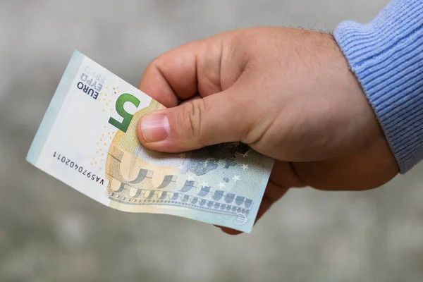Un homme donne de l'argent. Tenir les billets en euros sur un dos flou — Photo