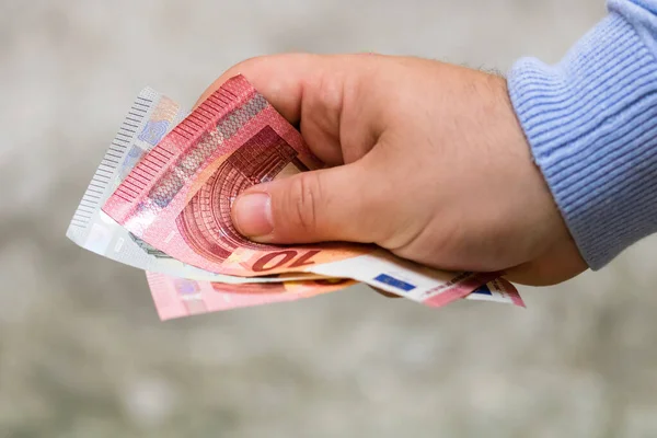 Man hands giving money. Holding EURO banknotes on a blurred back