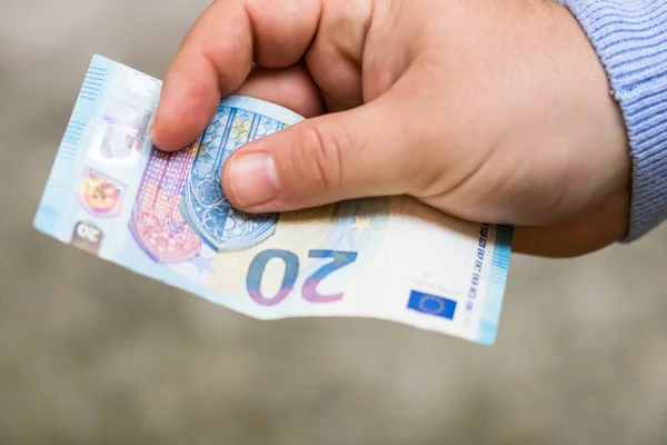 O homem dá dinheiro. Detenção de notas de euro num verso desfocado — Fotografia de Stock
