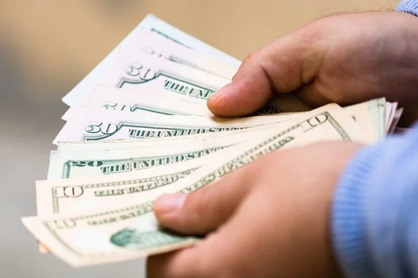 Man hands counting money, counting US dollars currency, close up