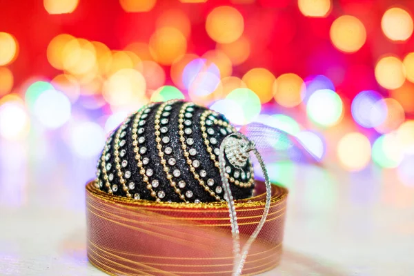 Zwart en glanzend kerstbal omgeven door een kleurrijke bloemenslinger. — Stockfoto