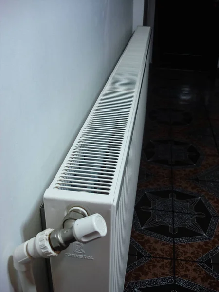 Beyaz metal ısıtma radyatörü odanın içindeki bir duvara monte edilmiş.. — Stok fotoğraf
