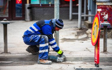 İnşaat işçisi kaldırım için asfalt kesiyor.