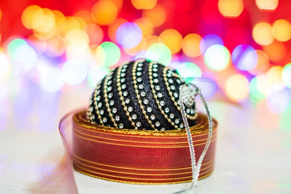 Чорний і блискучий різдвяний м'яч в оточенні барвистої гірлянди . — стокове фото