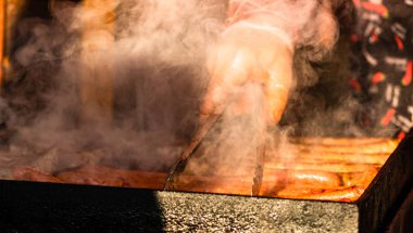 Şef kış İsa 'sında ızgarada ev yapımı sosis pişiriyor.