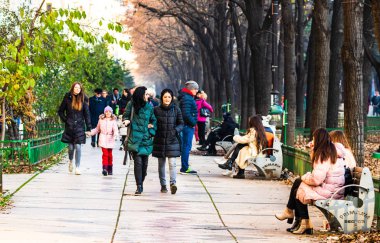 B şehir merkezindeki işlek caddede kışlık paltolu insanlar yürüyor.