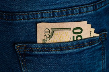 Banknotlar kapanıyor, para kot pantolonun cebinde. Dolarlar öne çıkıyor.
