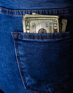 Banknotlar kapanıyor, para kot pantolonun cebinde. Dolarlar öne çıkıyor.