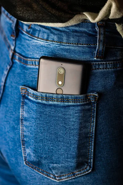 Cierre el teléfono inteligente en el bolsillo trasero de los jeans. Negocios y moda c — Foto de Stock