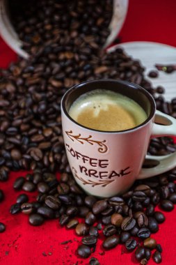 Bir fincan kahve, kırmızı arka planda kavrulmuş kahve çekirdekleri, üst manzara.,