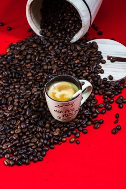 Bir fincan kahve, kırmızı arka planda kavrulmuş kahve çekirdekleri, üst manzara.,