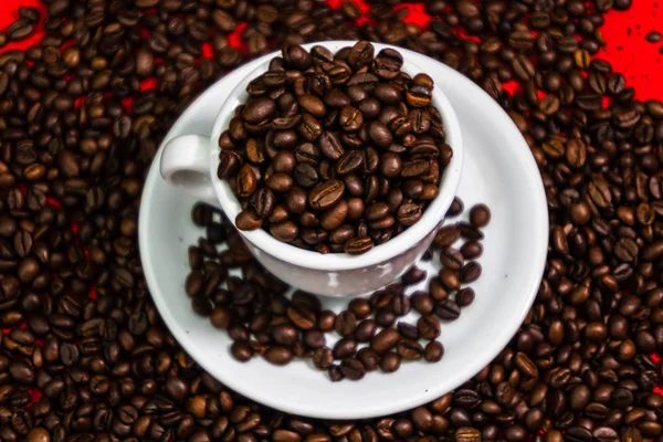 Coffee cup with roasted beans on red and coffee beans background