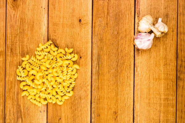 Vue détaillée de l'ail, des macaronis et des pâtes sur fond en bois , — Photo