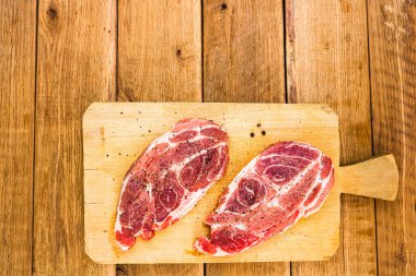 Ahşap kesme tahtasının üzerinde soslu domuz pirzolası.